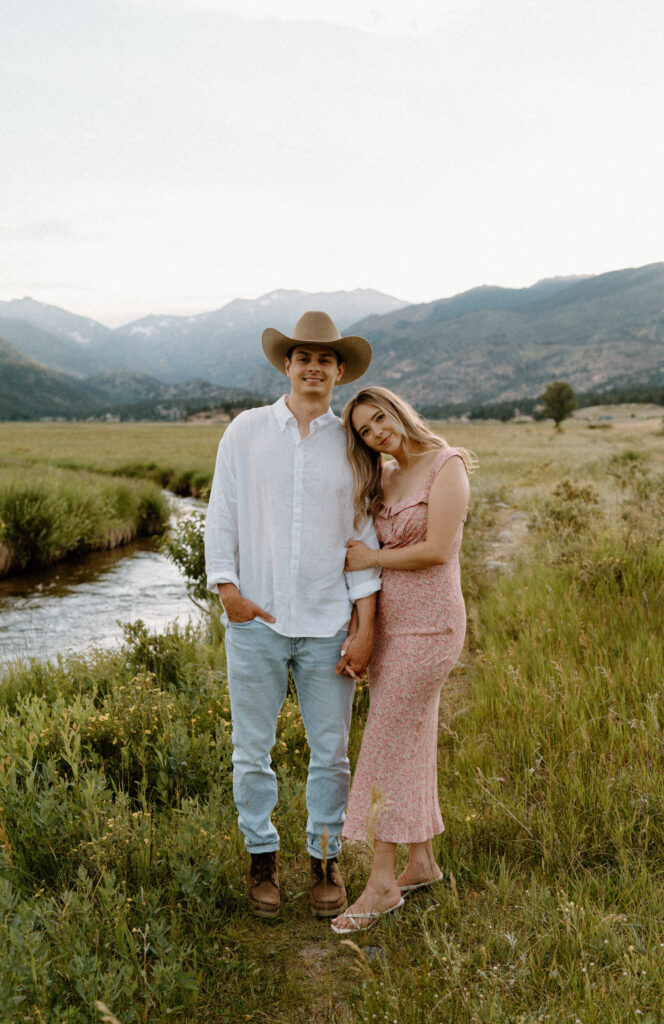 Couple smiling and holding hands at Rocky Mountain National Park during engagement session