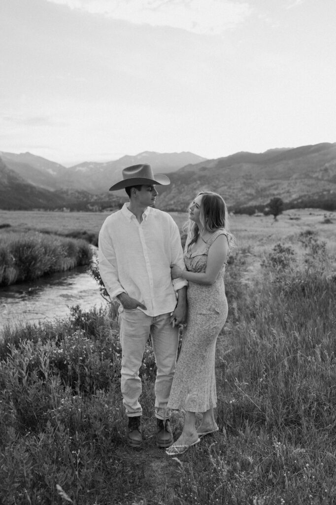 Couple smiling at each other by a river at Rocky Mountain National Park during an engagement session