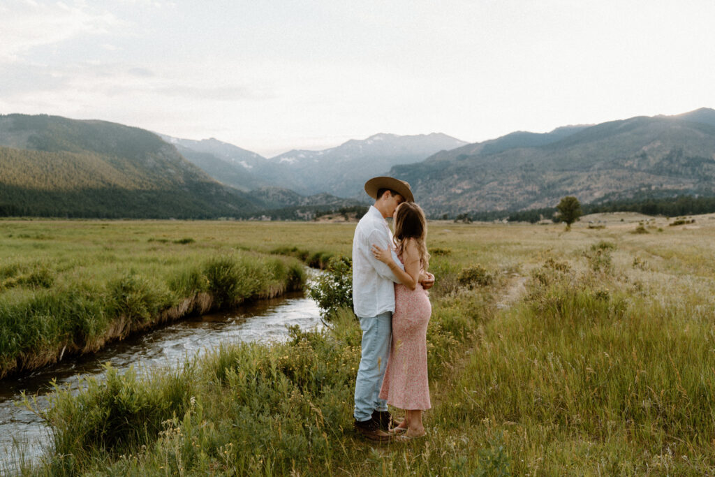 Couple kissing by a river at Rocky Mountain National Park during an engagement session