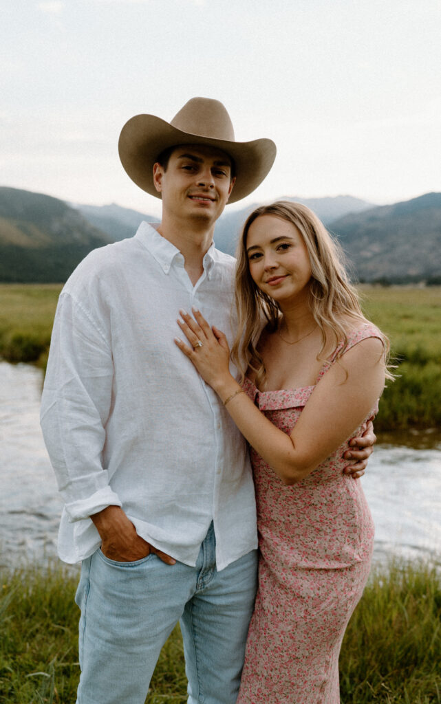 Couple smiling at camera during an engagement session at Rocky Mountain National Park by a river