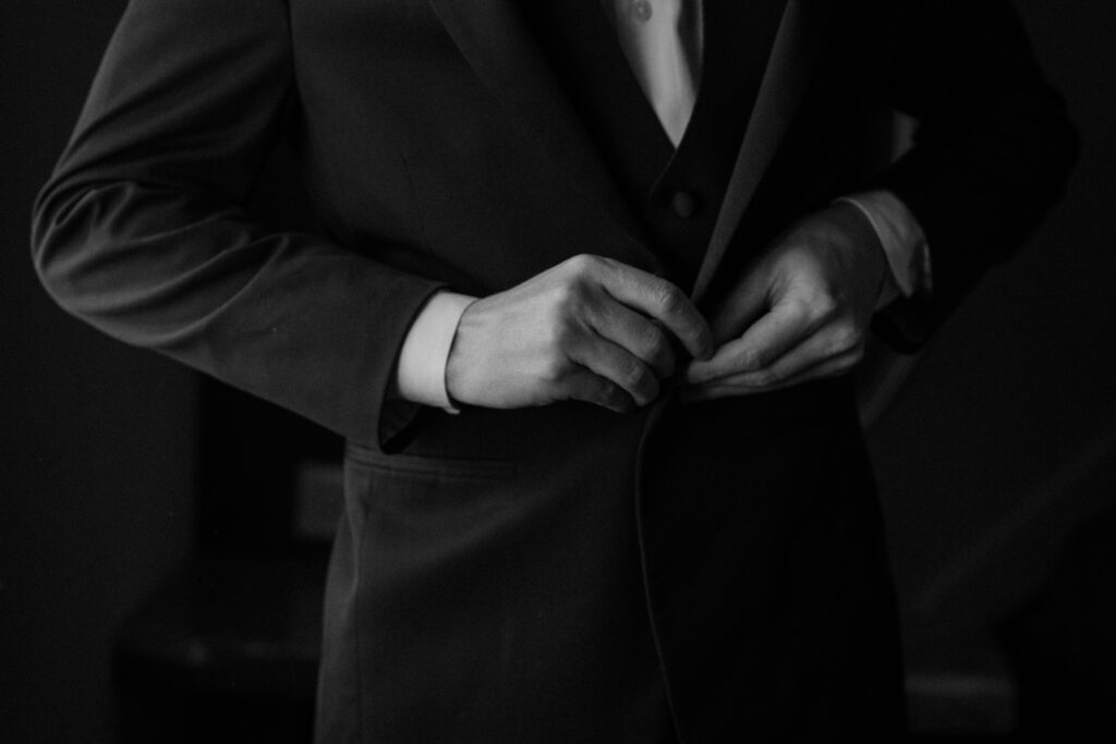 Groom buttoning suit jacket on wedding day at Woodlands