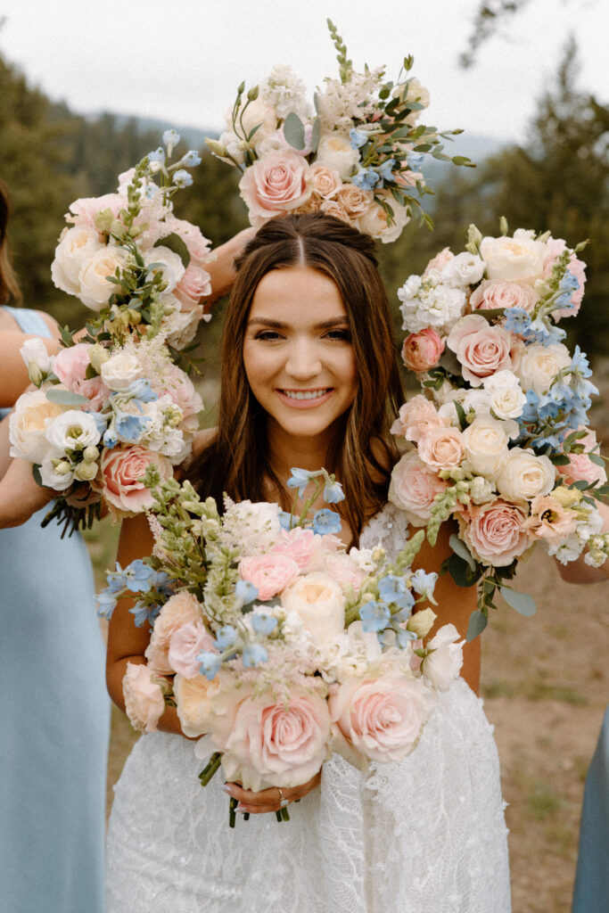 Bride smiling in her bridesmaid's bouquets of flowers on wedding day at Woodlands