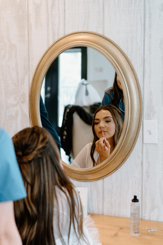 Bride putting on lipstick on wedding day at Woodlands