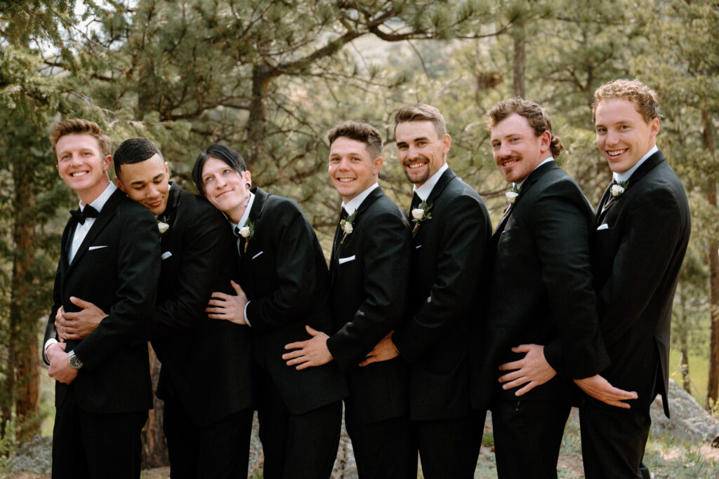 Groom and groomsmen hugging on wedding day at Woodlands 