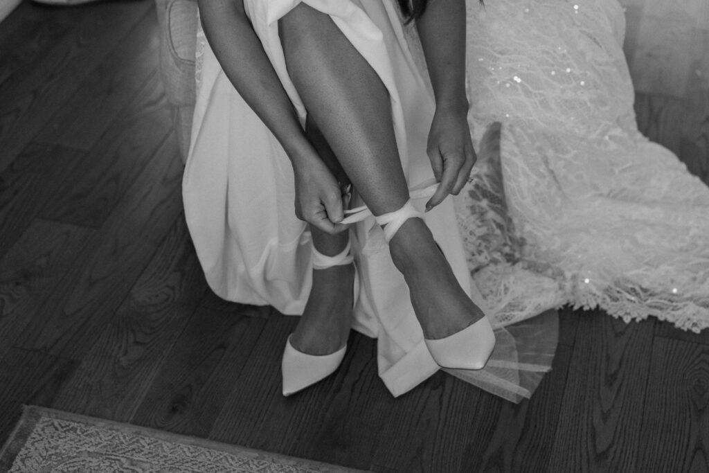 Bride tying her heels on wedding day at Woodlands