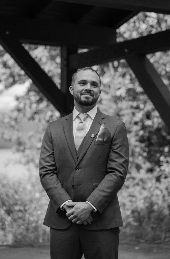 Groom smiling watching bride walk down the aisle during an elopement at Glacier National Park