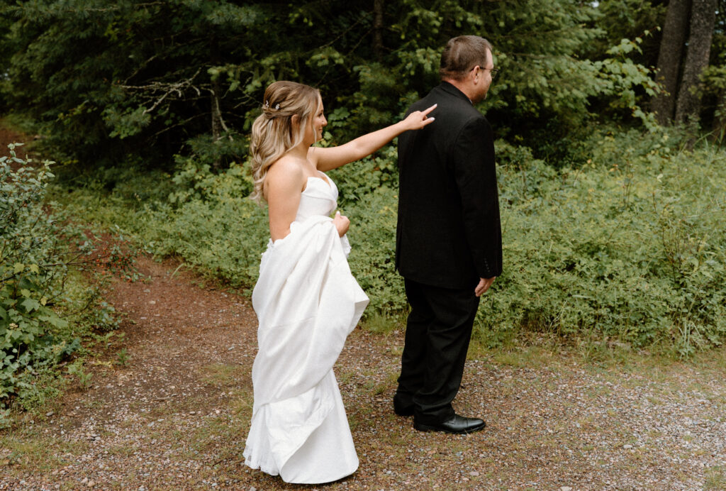 Bride tapping on dad's shoulder during first look at an elopement at Glacier National Park