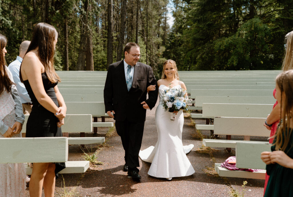 Bride and dd smiling while walking down the aisle at Glacier National Park during an elopement 