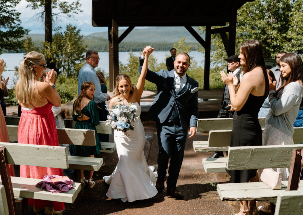Bride and groom walking down the aisle cheering during an elopement at Glacier National Park