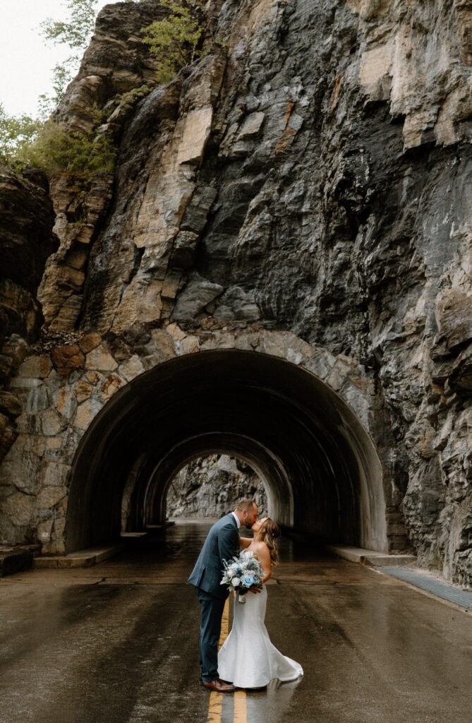 Bride and groom kissing in a tunnel during an elopement at Glacier National Park