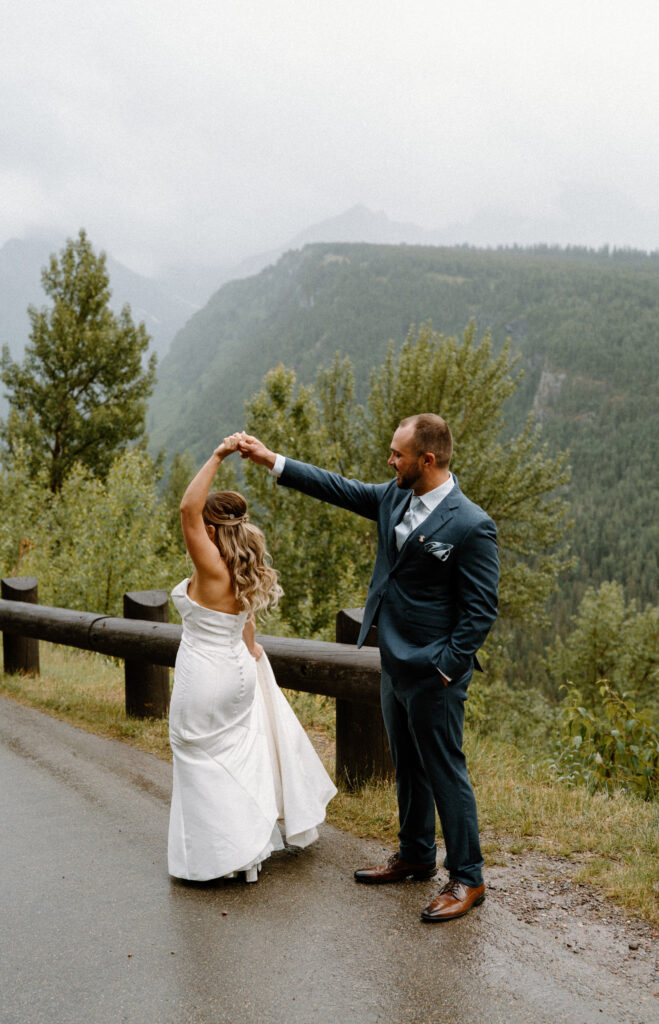 Groom spinning bride on a road in Glacier National Park during an elopement