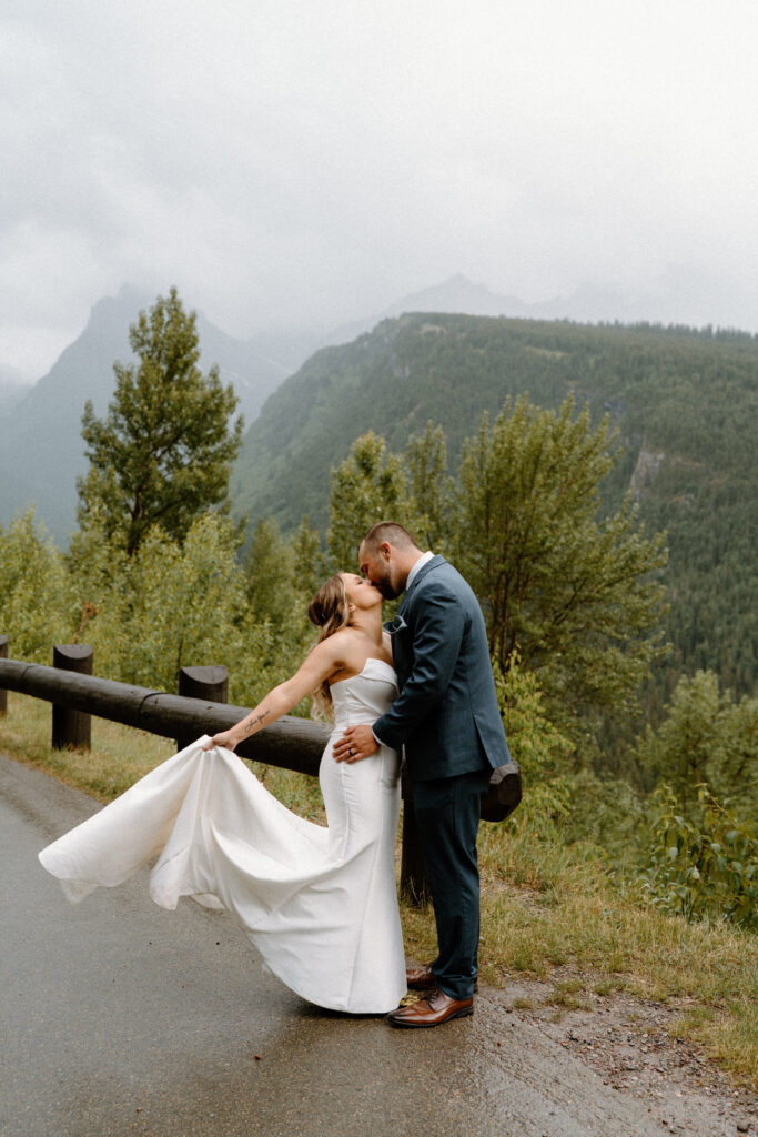 Bride and groom kissing on a road in Glacier National Park during an elopement 