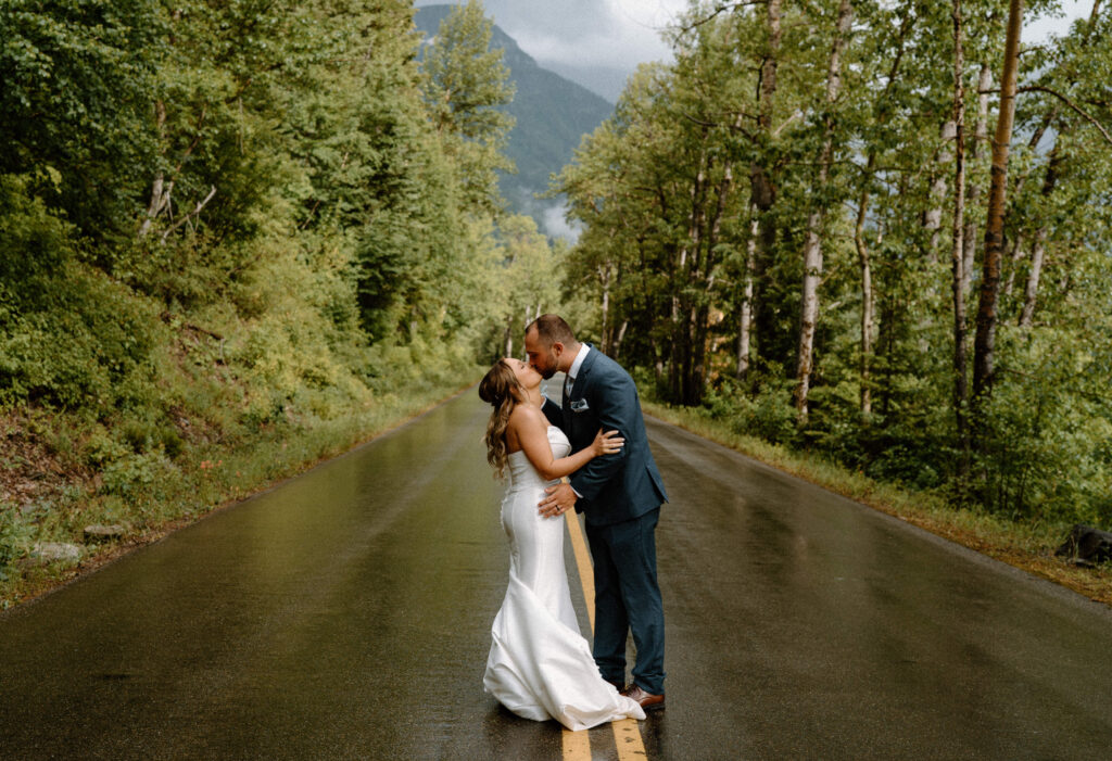 Bride and groom kissing in the middle of the road at Glacier National Park during an elopement