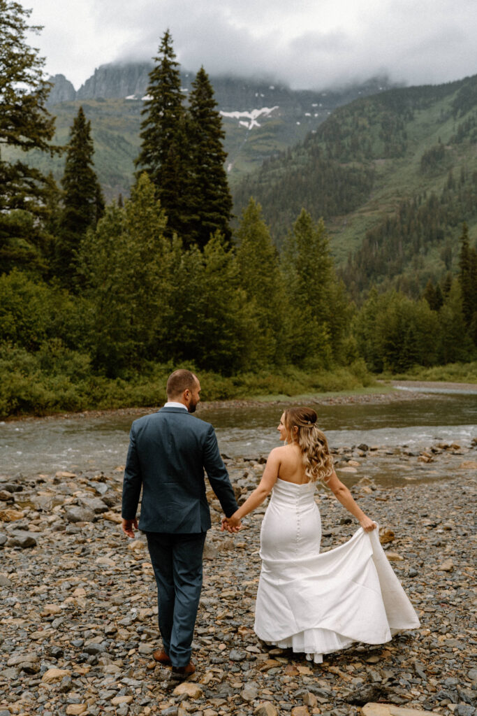 Bride and groom walking near a river in Glacier National Park during an elopement
