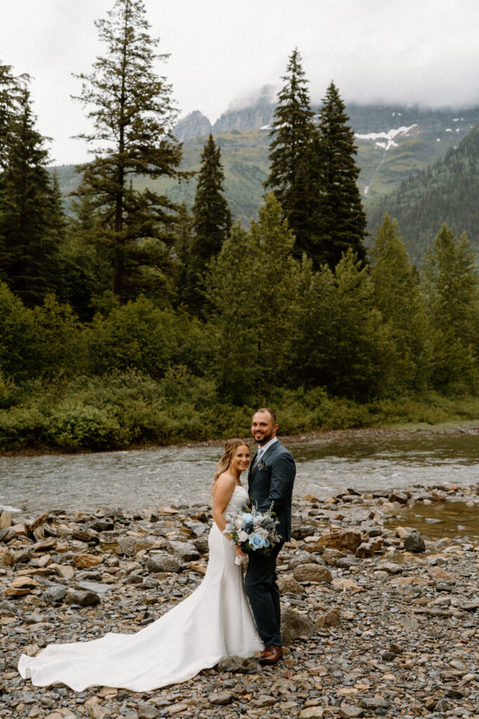 Bride and groom smiling near a river during an elopement at Glacier National Park