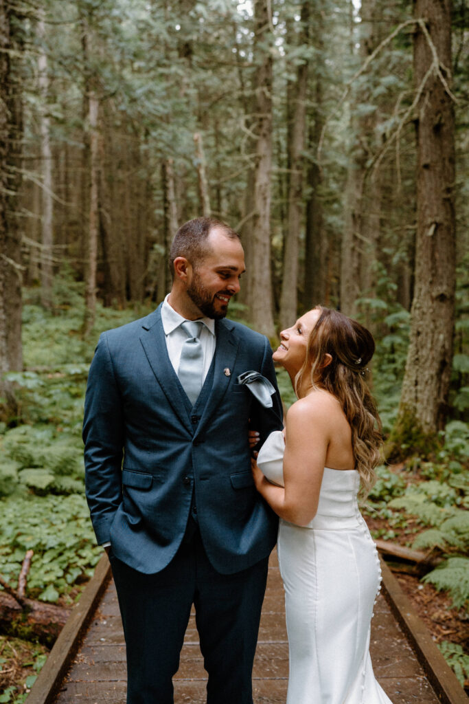Bride and groom smiling at each other on a path in Glacier National Park