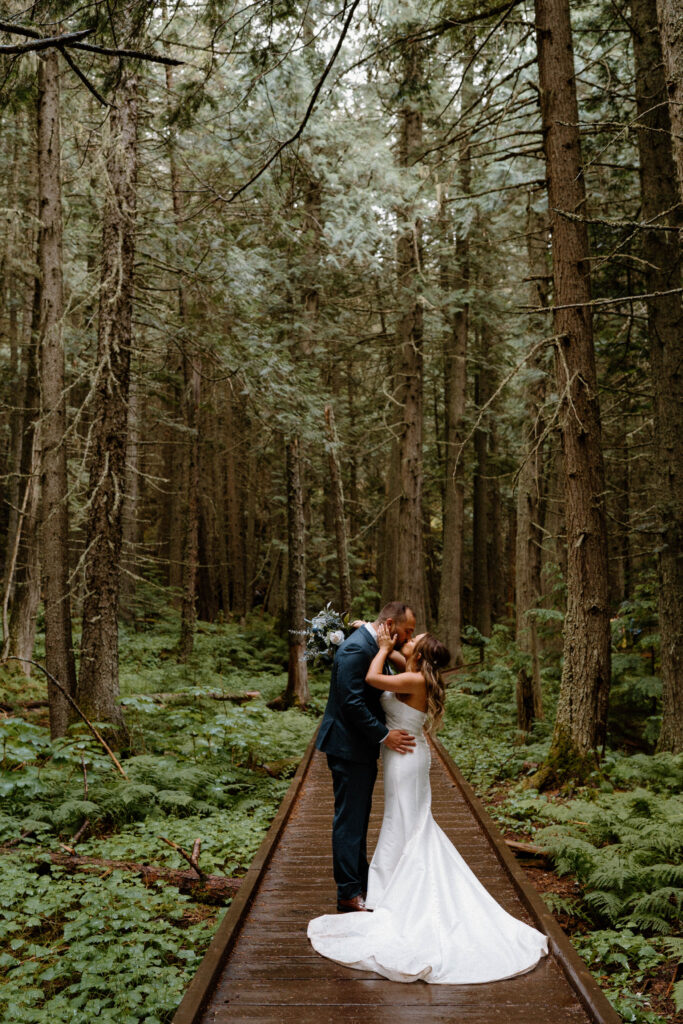 Bride and groom kissing on a path in Glacier National Park