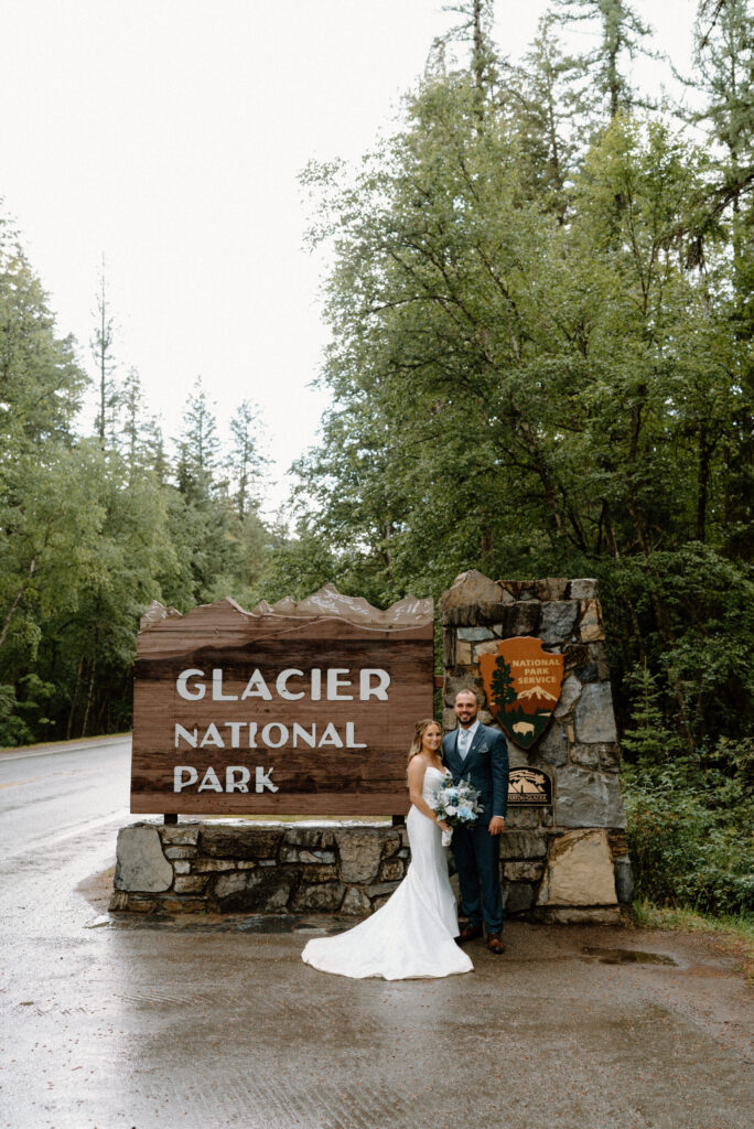 Bride and groom smiling at the Glacier National Park sign during an elopement