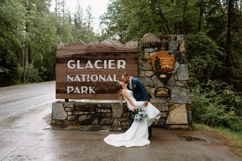 Bride and groom kissing by the Glacier National Park sign during an elopement
