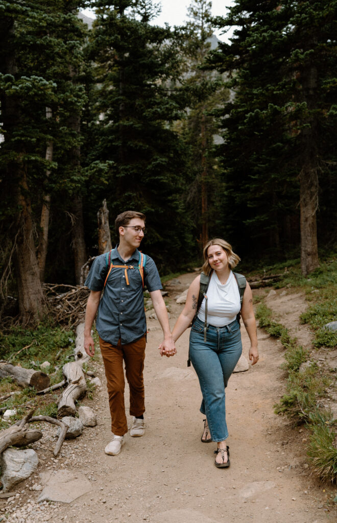 Couple hiking and holding hands during an engagement session at Lake Isabelle