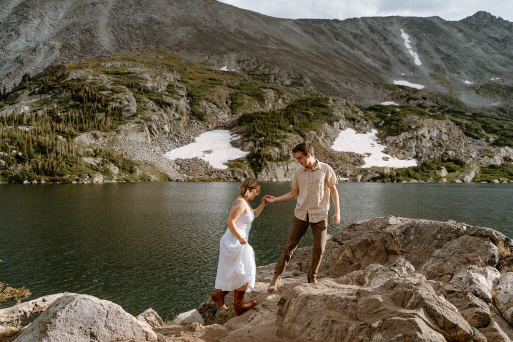 Couple walking up a rock at Lake Isabelle during an engagement session