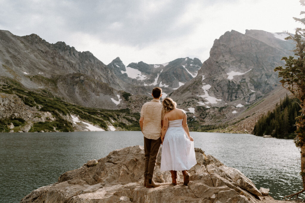 Couple standing on a rock admiring Lake Isabelle during an engagement session