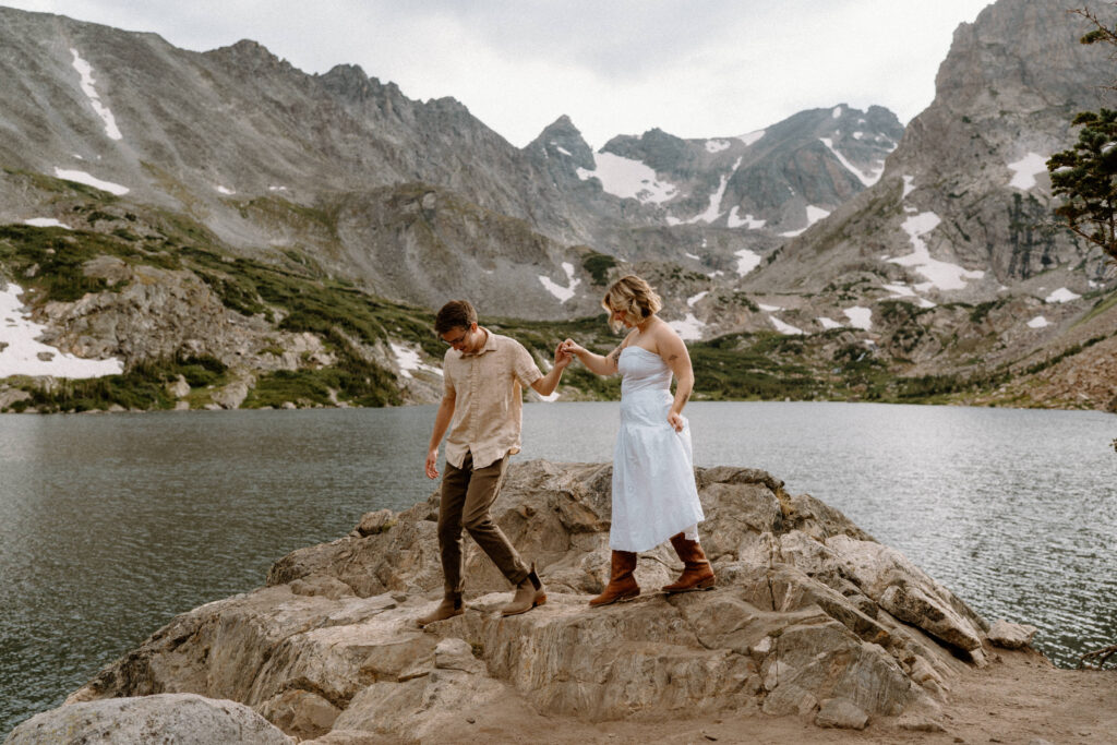 Couple walking down a rock during an engagement session at Lake Isabelle