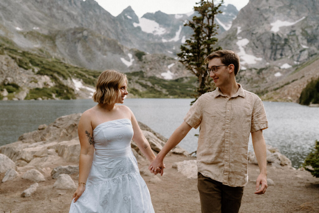 Couple holding hands while hiking during an engagement session at Lake Isabelle