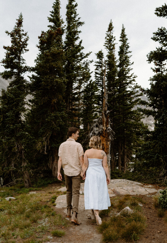 Couple hiking down a path during an engagement session at Lake Isabelle