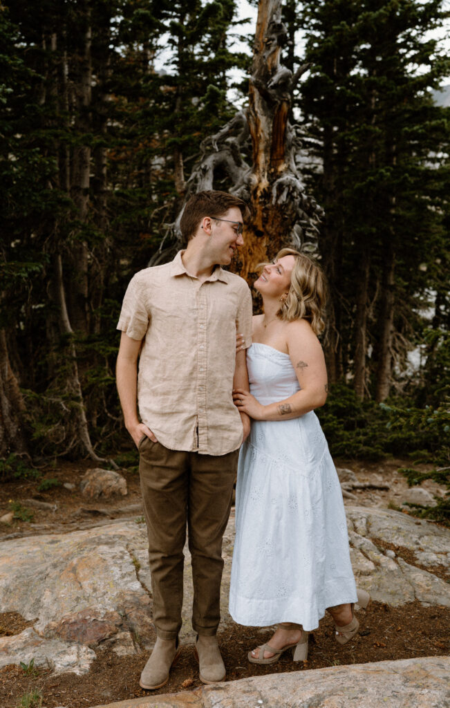 Couple smiling at each other on a hike at Lake Isabelle during an engagement session