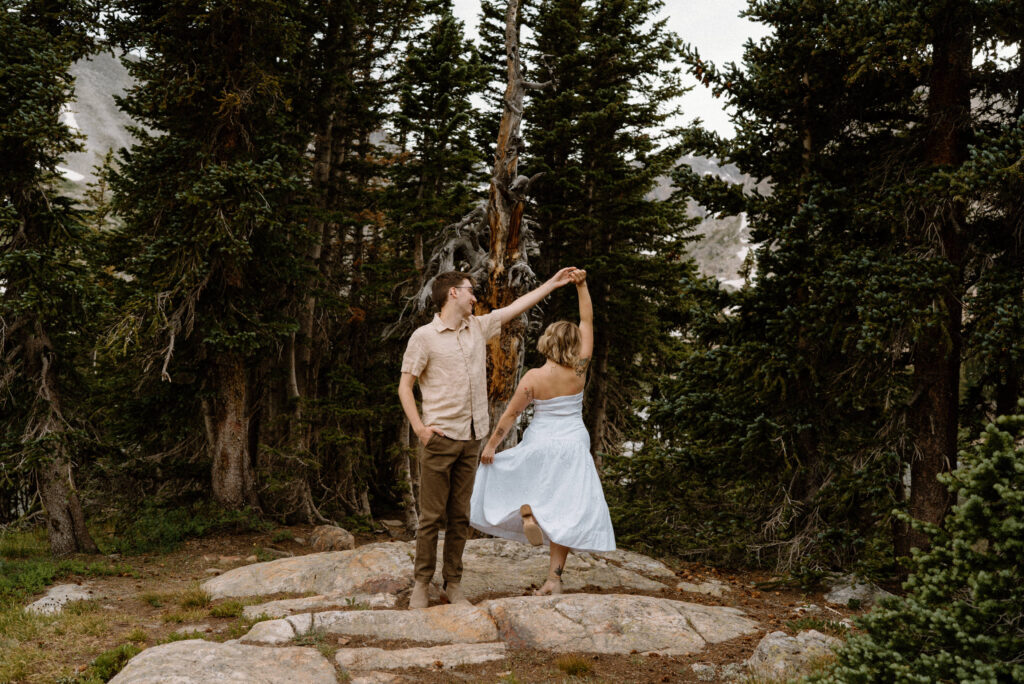 Fiancé twirling fiancée on a rock at Lake Isabelle during engagement session