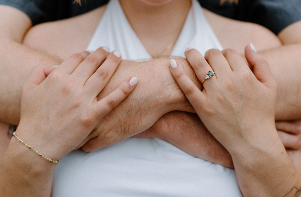 Fiancé hugging fiancée showing engagement ring during an engagement session at Lake Isabelle