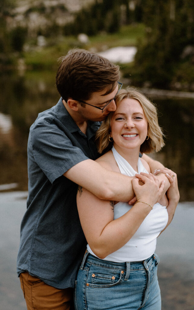 Fiancé kissing fiancée's forehead during an engagement session at Lake Isabelle