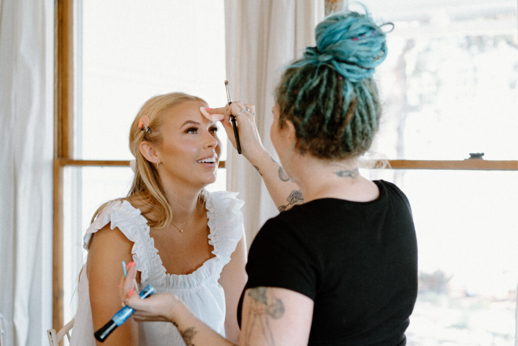Bride getting makeup done on wedding day at The Manor House