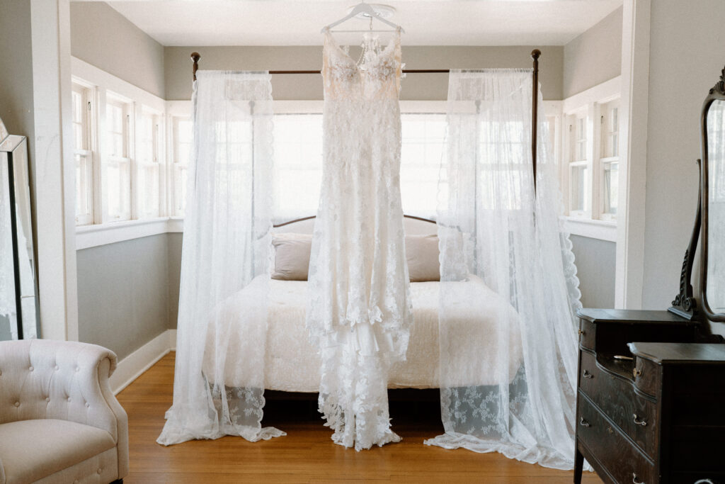 Wedding dress hanging on a bed at The Manor House on wedding day