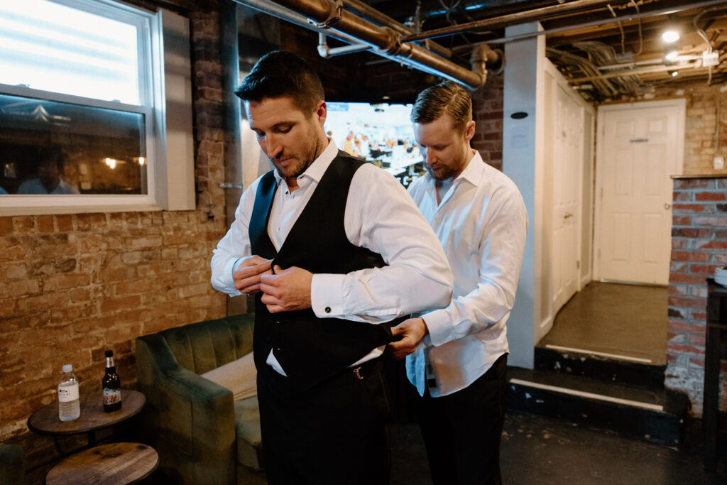 Groom putting on suit jacket on wedding day at The Manor House