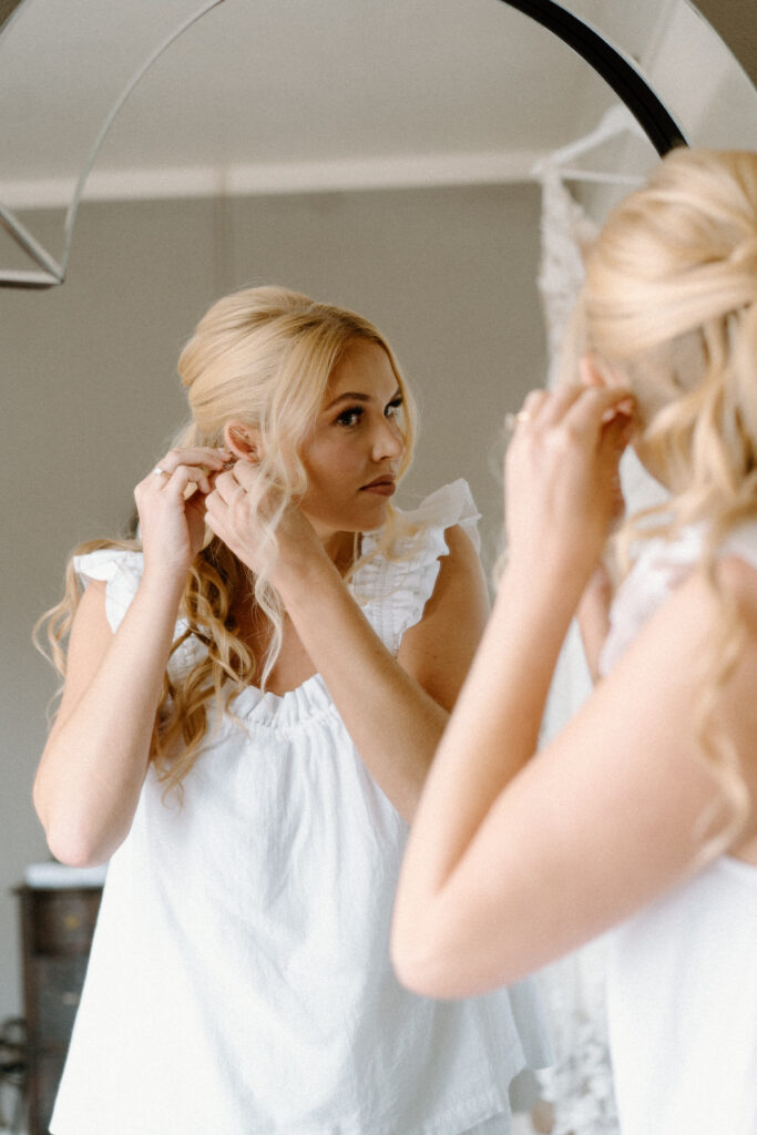 Bride putting earrings in on wedding day at The Manor House