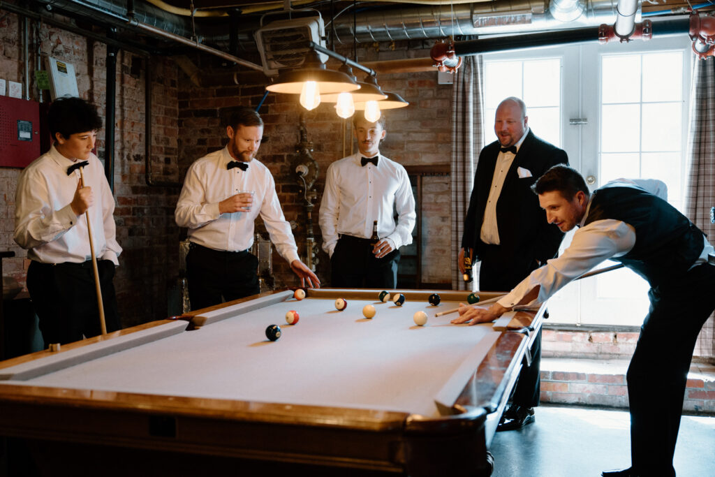 Groom and groomsmen playing pool on wedding day at The Manor House