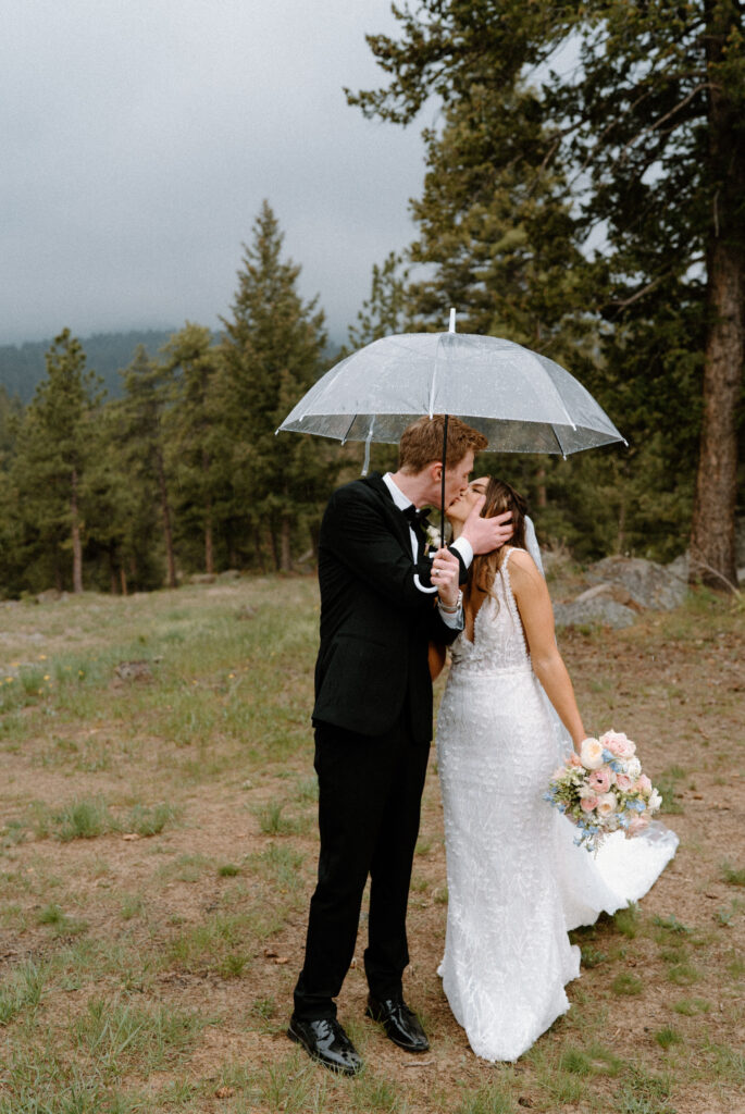 Bride and groom kissing in the rain on wedding day at Woodlands