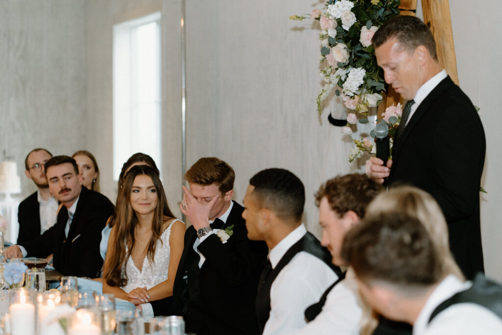 Bride and groom smiling during speeches on wedding day at Woodlands