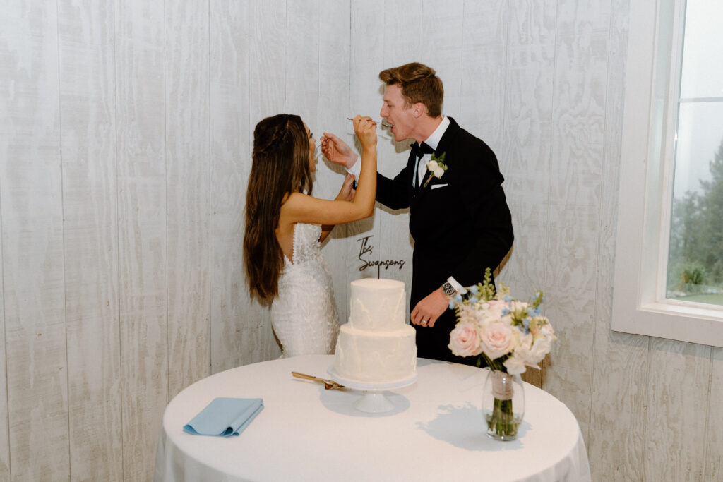 Bride and groom feeding each other cake on wedding day at Woodlands