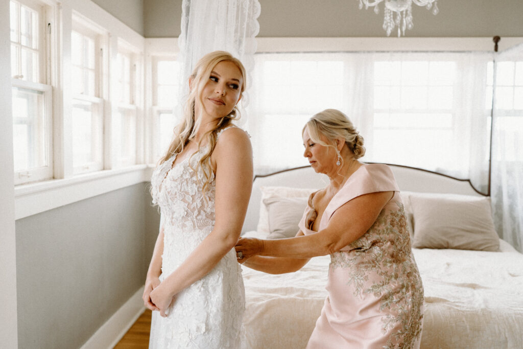 Mom helping bride into her dress on wedding day at The Manor House