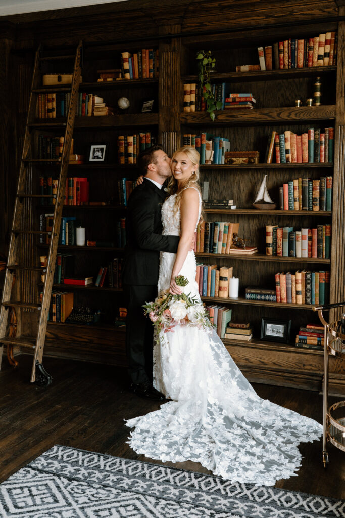 Bride smiling at the camera while groom hugs her on wedding day at The Manor House