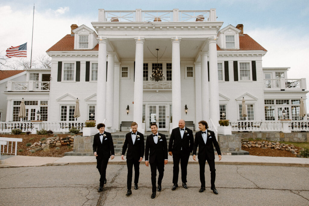 Groom and groomsmen walking outside The Manor House on wedding day