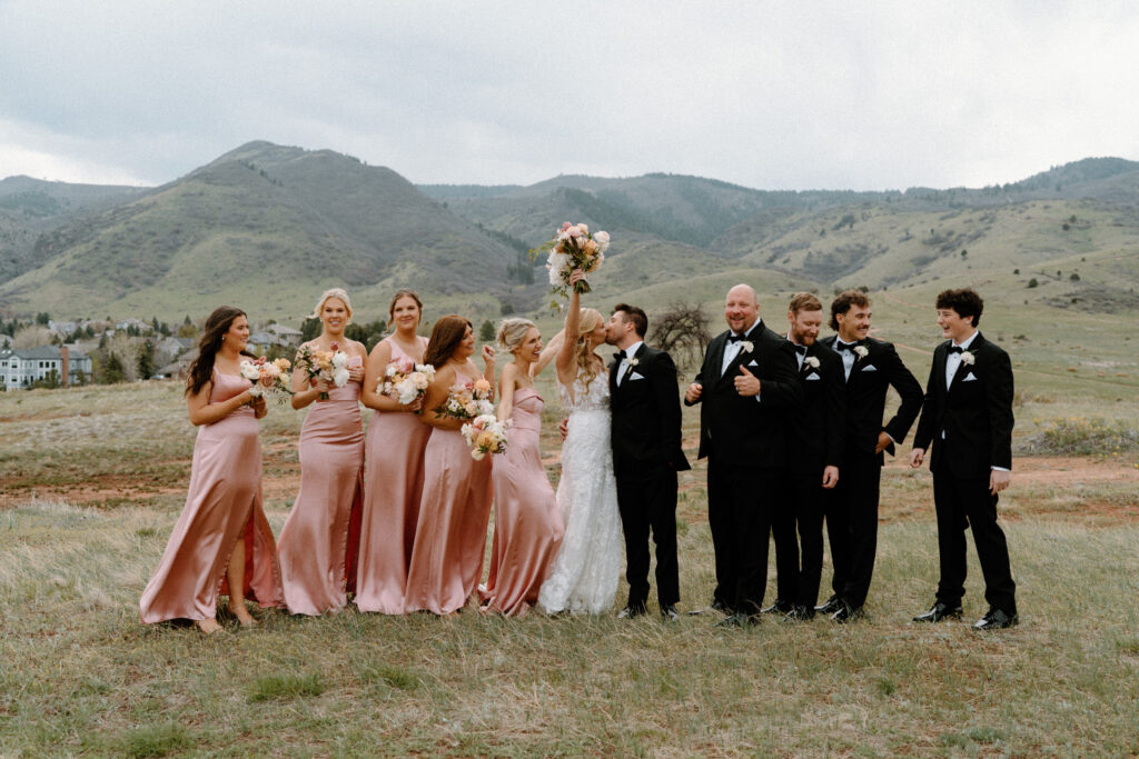 Wedding party cheering as bride and groom kiss on wedding day at The Manor House