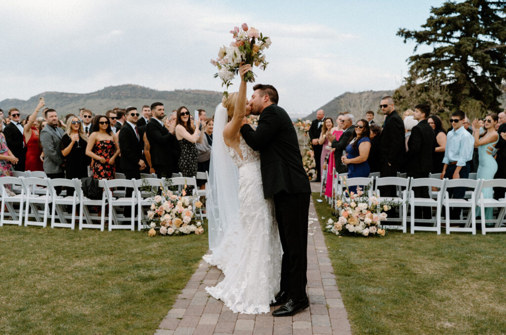 Bride and groom kissing at the end of aisle after ceremony at The Manor House
