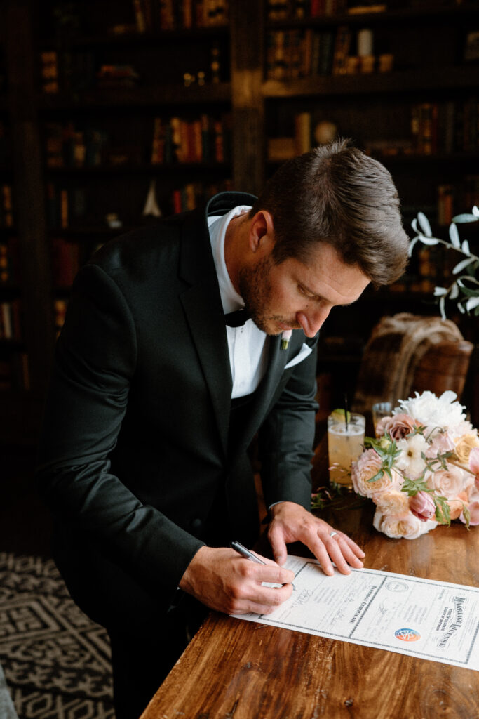 Groom signing marriage license on wedding day at Manor House