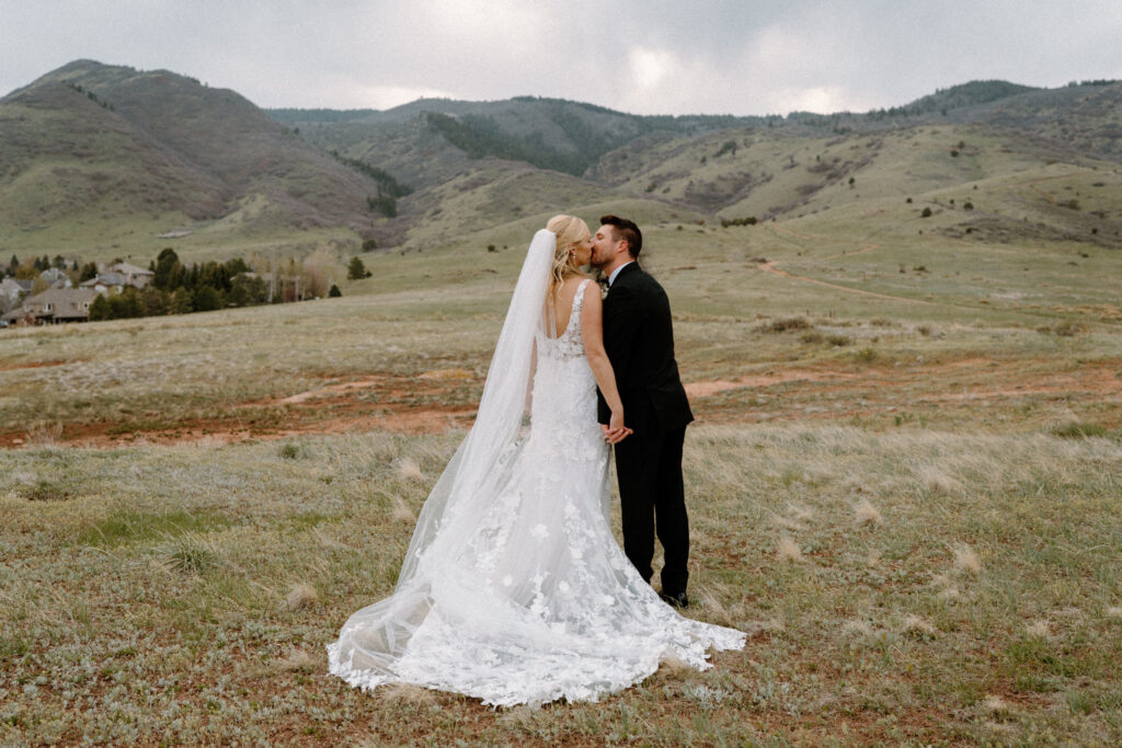 Bride and groom kissing in a field at Manor House on wedding day