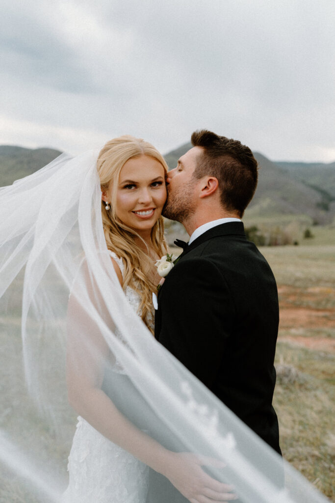 Groom kissing brides head through veil at The Manor House