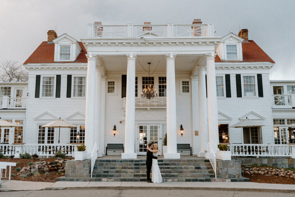 Bride and groom kissing outside Manor House on wedding day